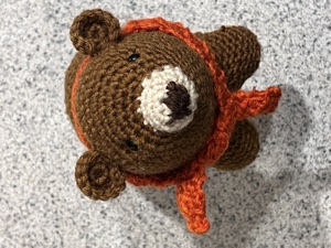Lumpy Bear amigurumi, a small brown crochet bear wearing an orange scarf
